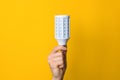 Closeup hand holding white led lighting bulb against a yellow wide background. concept of idea, energy and ecology Royalty Free Stock Photo