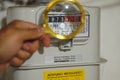 hand holds a golden magnifying glass and zoom display of the gas meter