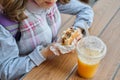 Closeup of hand of kid eating burger and drinking orange juice Royalty Free Stock Photo