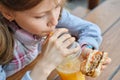Closeup of hand of kid eating burger and drinking orange juice Royalty Free Stock Photo