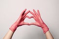 Closeup of a hand in latex rubber medical pink gloves folded into a heart sign. Isolated on white background. Concept love couple Royalty Free Stock Photo