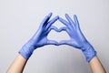 Closeup of a hand in latex rubber medical purple gloves folded into heart sign. Isolated on white background. Concept love couple Royalty Free Stock Photo