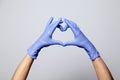 Closeup of a hand in latex rubber medical purple gloves folded into a heart sign. Isolated on white background. Concept love Royalty Free Stock Photo