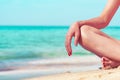 Closeup hand and leg of woman sit on sand beach at seaside. Happy young Asian woman relax and enjoy holiday at tropical paradise Royalty Free Stock Photo