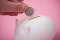 hand of man putting euro coin in white piggy bank on pink background Royalty Free Stock Photo