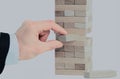 The tower from wooden blocks and man`s hand take one block Royalty Free Stock Photo