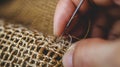 Closeup of hand with needle threading in clothes fixing holes