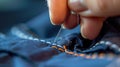 Closeup of hand with needle threading in clothes fixing holes