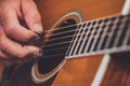 Closeup of a hand of older man picking or playing strings of acoustic guitar