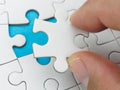 Closeup hand placing last piece puzzle Royalty Free Stock Photo