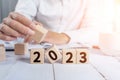 Closeup of the hand placing wooden cubes on the table. 2023 new year plans concept.