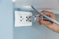 Closeup hand plug in wall socket electricity to power electric appliance