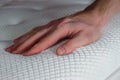 closeup of a hand pressing down on an orthopedic pillow, highlighting firmness