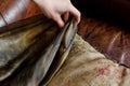 closeup of a hand pulling a silk scarf from under a leather armchair cushion