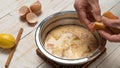 Closeup of a hand putting bread on a bowl of milk, cracked eggshells, lemon, and cinnamon Royalty Free Stock Photo