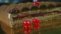 Closeup hand rotates plate with half of chocolate cream cake with cherry interlayer