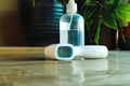 Closeup of hand sanitizer bottle and thermometer isolated on wooden floor covid-19 safety objects