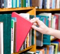 Closeup hand selecting book from a bookshelf