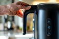 closeup of hand switching on modern electric kettle with led indicator