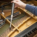 Hand and tools of tuner working on grand piano