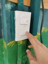 Closeup of hand turning on a light switch on a green wall