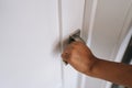 Closeup hand of unrecognizable African woman opening white modern door with minimalist handle to bedroom. Closeup