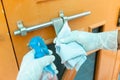 Closeup Of Hand Wearing Protective Gloves cleaning and disinfecting / sanitizing door handles during coronavirus epidemic.