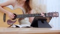 Closeup hand woman sitting on sofa looking tablet and compose a song for practice music with guitar in living room.