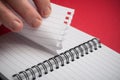 hand of woman tearing a page of spirales note book on red background Royalty Free Stock Photo