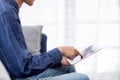 Closeup hand of young attractive asian man resting using browsing tablet computer on sofa at home. Royalty Free Stock Photo