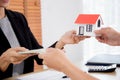 Closeup hand of young realtor woman giving house model to hands customer while client giving money with approval. Royalty Free Stock Photo