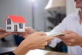 Closeup hand of young realtor woman giving house model to hands customer while client giving money with approval about real estate Royalty Free Stock Photo
