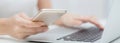 Closeup hand of young woman working laptop computer and reading smartphone on internet online on desk. Royalty Free Stock Photo