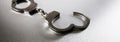 Closeup of handcuffs on obscure stainless steel background for prison