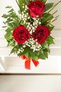 Closeup on a handmade red box with floral arrangement. The floral arrangement is three red roses and green leaves. A wonderful