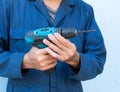 Closeup hands of Asian mechanic holding cordless drill isolated on blue background