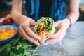 closeup on hands assembling a veggie wrap