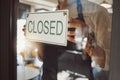 Closeup on hands of businessman hanging a closed sign. Business owner hanging a closed message in cafe door. Hands of Royalty Free Stock Photo