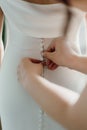 Closeup of hands buttoning bride& x27;s dress