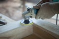 Closeup hands of carpenter using a power tool wood sander in workshop