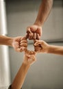 Closeup of hands of colleagues with fists joined. Zoom into hands of coworkers fists joined from below. Group of Royalty Free Stock Photo