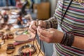 Closeup of the hands of a craftswoman making bracelets with leather in her workshop