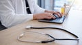 Closeup, hands and doctor typing, stethoscope and telehealth in office, update data and connection for communication