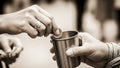 Closeup of hands exchanging a coin into a metal cup Royalty Free Stock Photo