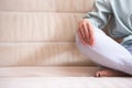 Closeup of Hands and Feet of Senior Woman Posing in Yoga Asana Pose on Couch indoors. Sitting with Folded Legs