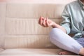 Closeup of Hands and Feet of Senior Woman Posing in Yoga Asana Pose on Couch indoors. Sitting with Folded Legs