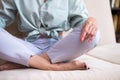 Closeup of Hands and Feet of Senior Woman Posing in Yoga Asana Pose on Couch indoors. Sitting with Folded Legs