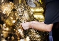 Closeup of hands gilding gold leaf sheet to Buddha statue in Thai temple Royalty Free Stock Photo