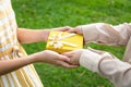 Closeup hands giving gift box,Asian daughter and mother with gift box in green nature background,parent giving her birthday little