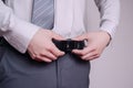 Closeup of the hands of a groom fixing his belt